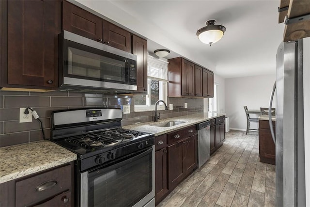 kitchen featuring sink, appliances with stainless steel finishes, dark brown cabinets, tasteful backsplash, and light wood-type flooring