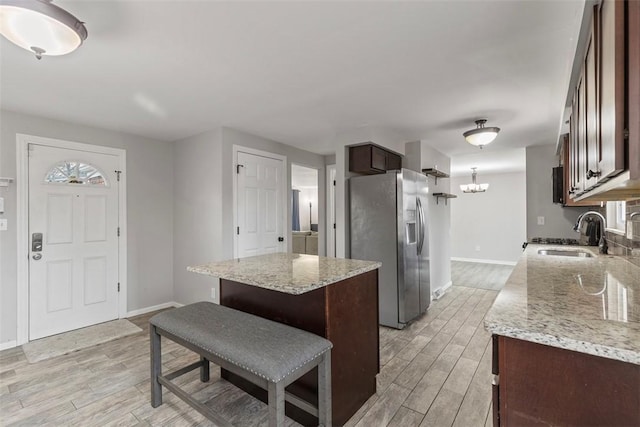 kitchen featuring light stone counters, stainless steel fridge, light hardwood / wood-style floors, and sink