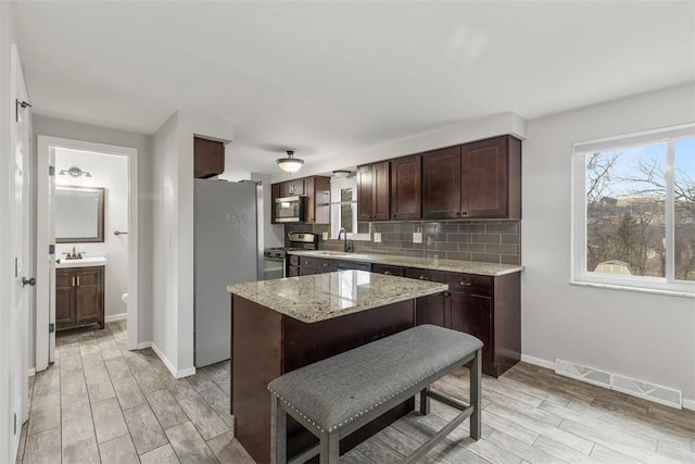 kitchen featuring a kitchen island, appliances with stainless steel finishes, sink, a kitchen breakfast bar, and decorative backsplash