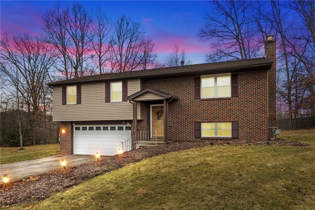 bi-level home with a garage and a yard