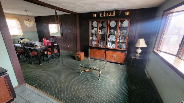 tiled dining area with beamed ceiling, a chandelier, and wood walls