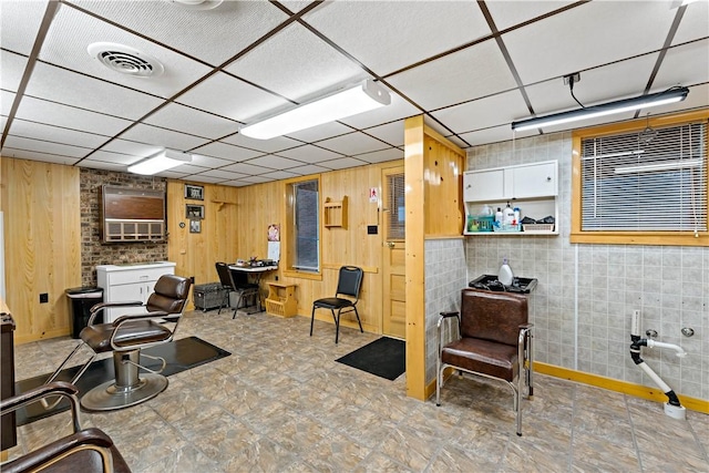 interior space featuring a paneled ceiling and wood walls