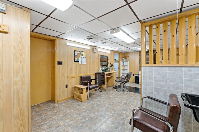 office space with a drop ceiling and wooden walls