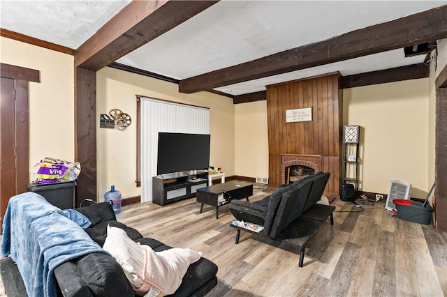 living room featuring beam ceiling, a fireplace, and light wood-type flooring