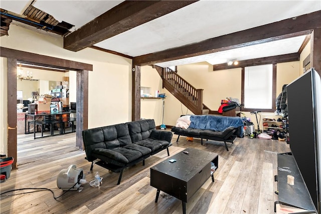 living room with beamed ceiling, a chandelier, and light wood-type flooring