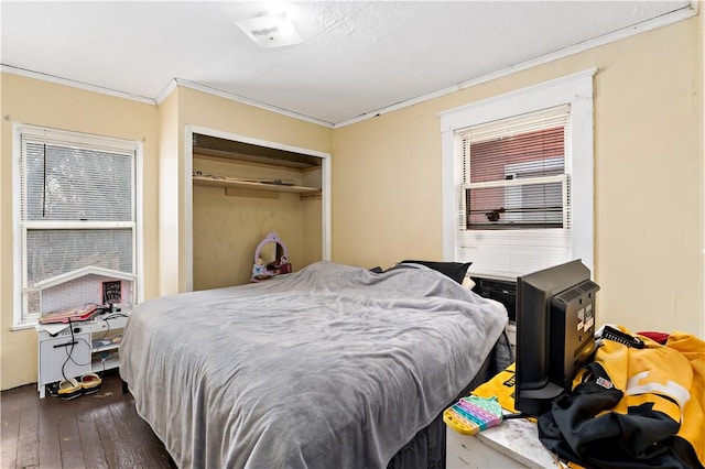 bedroom with ornamental molding, dark wood-type flooring, and a closet