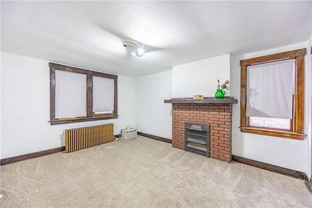 living room featuring radiator, carpet floors, and a brick fireplace