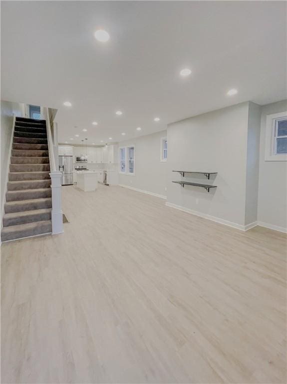 basement featuring light hardwood / wood-style flooring and stainless steel fridge