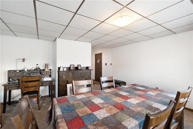 dining room with a paneled ceiling and dark colored carpet