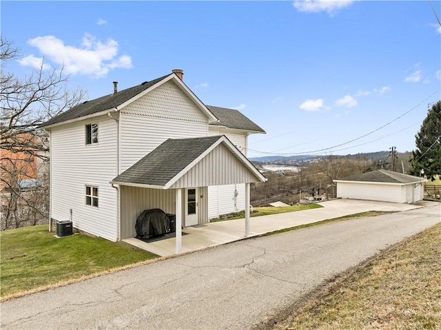 view of side of property featuring cooling unit, a garage, an outdoor structure, and a lawn