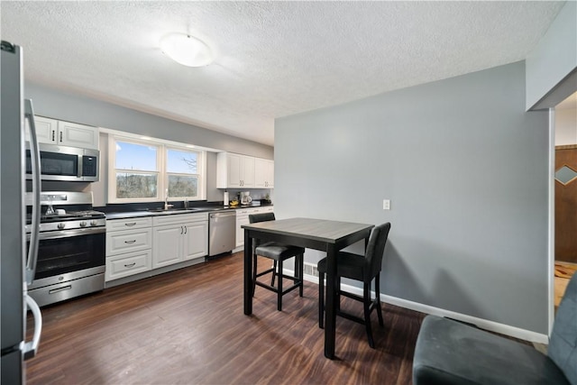 kitchen featuring dark hardwood / wood-style flooring, sink, stainless steel appliances, and white cabinets