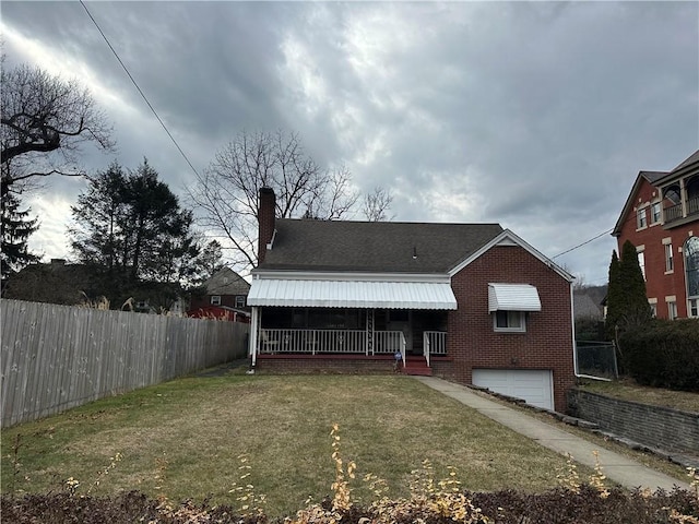 back of property with a garage, brick siding, fence, a yard, and a chimney