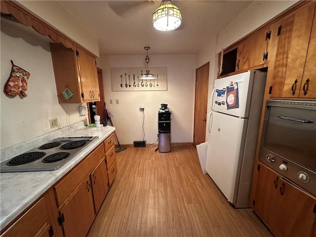 kitchen with light wood-style flooring, brown cabinets, freestanding refrigerator, and stainless steel electric stovetop