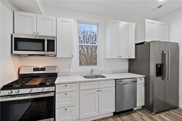 kitchen with stainless steel appliances, sink, and white cabinets