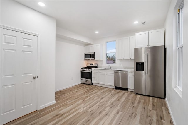 kitchen with sink, light hardwood / wood-style flooring, stainless steel appliances, and white cabinets