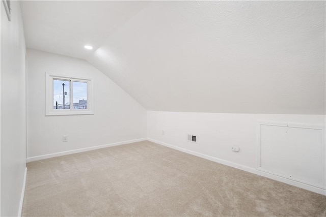 bonus room with light colored carpet and lofted ceiling