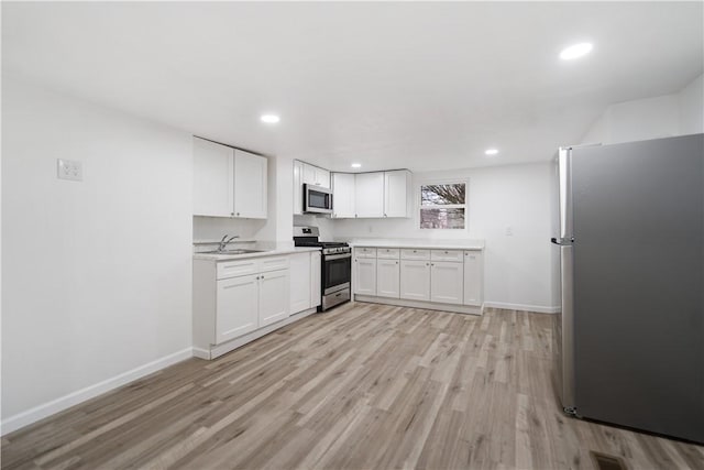 kitchen featuring light wood-type flooring, appliances with stainless steel finishes, sink, and white cabinets