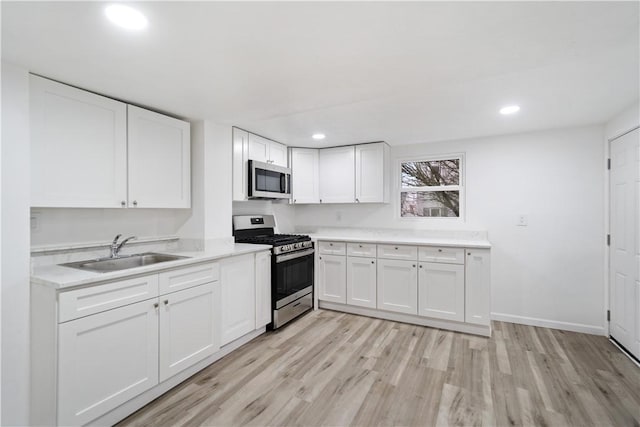 kitchen featuring stainless steel appliances, light hardwood / wood-style floors, sink, and white cabinets