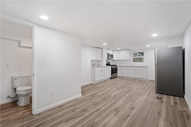 kitchen featuring stainless steel appliances, sink, white cabinets, and light hardwood / wood-style floors