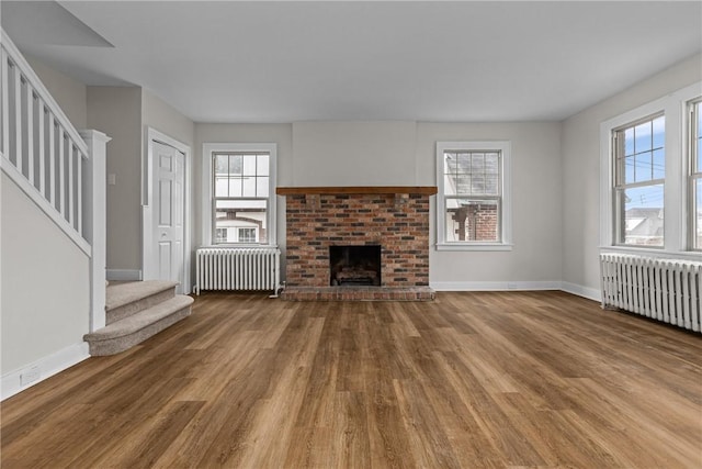 unfurnished living room featuring stairs, radiator heating unit, and plenty of natural light