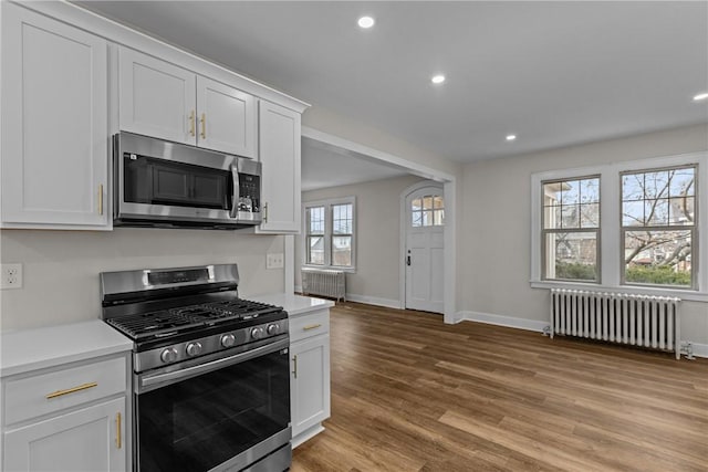 kitchen featuring appliances with stainless steel finishes, light countertops, radiator heating unit, and light wood-style floors