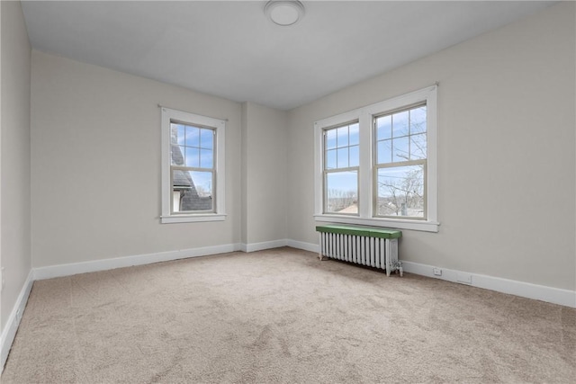 carpeted spare room featuring baseboards and radiator