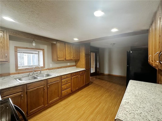 kitchen with black refrigerator, sink, light hardwood / wood-style floors, and a textured ceiling