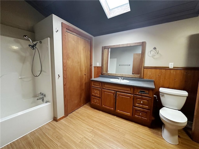 full bathroom with toilet, bathtub / shower combination, a skylight, vanity, and hardwood / wood-style flooring