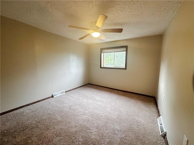 carpeted empty room with ceiling fan and a textured ceiling