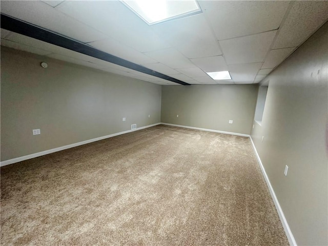 basement with a paneled ceiling and carpet flooring