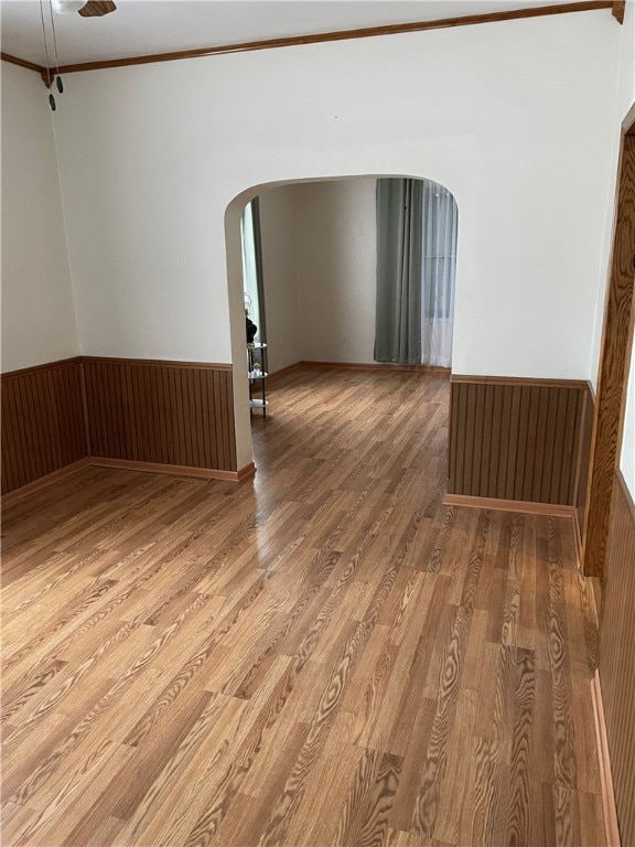 unfurnished room featuring hardwood / wood-style flooring, wooden walls, and crown molding