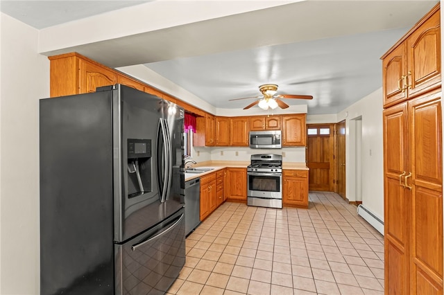 kitchen featuring sink, light tile patterned floors, a baseboard radiator, appliances with stainless steel finishes, and ceiling fan