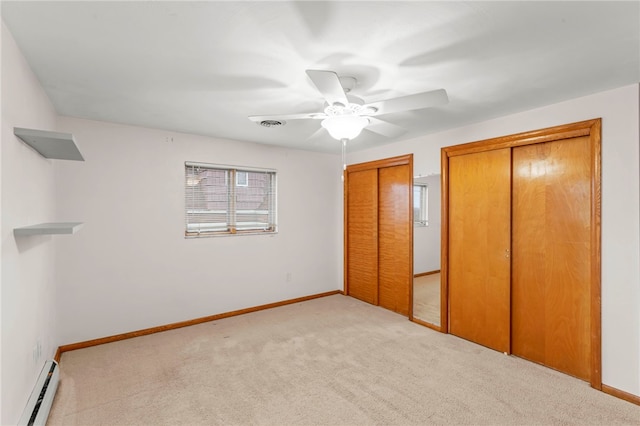 unfurnished bedroom featuring a baseboard heating unit, light colored carpet, multiple closets, and ceiling fan