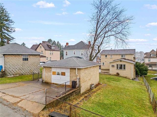 back of house featuring a garage, a yard, and an outbuilding