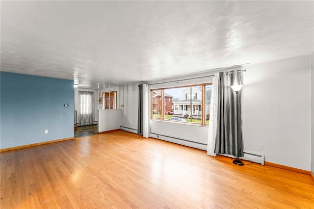 empty room with a baseboard radiator, plenty of natural light, and light hardwood / wood-style floors