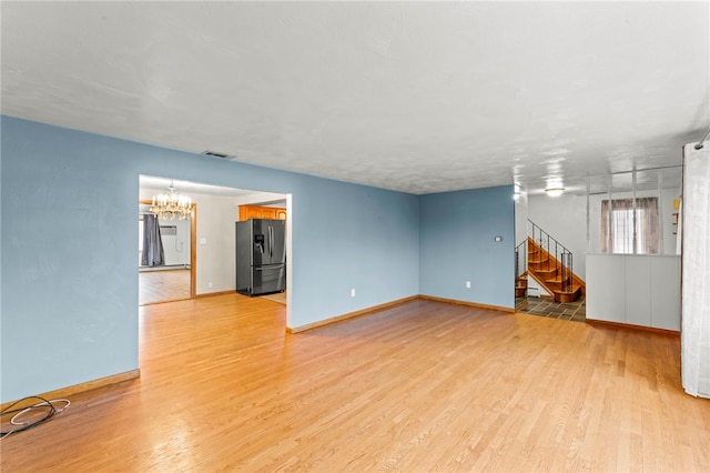 unfurnished living room featuring a chandelier and light hardwood / wood-style flooring