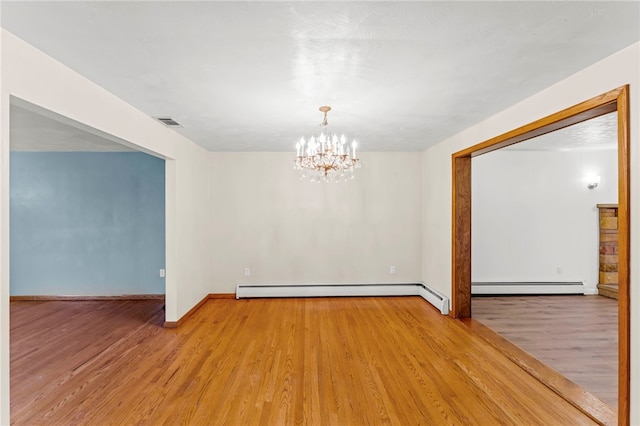 spare room with an inviting chandelier, a baseboard radiator, and light hardwood / wood-style floors