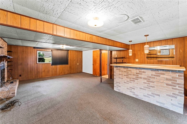 bar with a brick fireplace, decorative light fixtures, wooden walls, and carpet