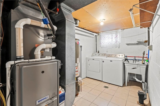 laundry room featuring washing machine and dryer, water heater, and light tile patterned floors