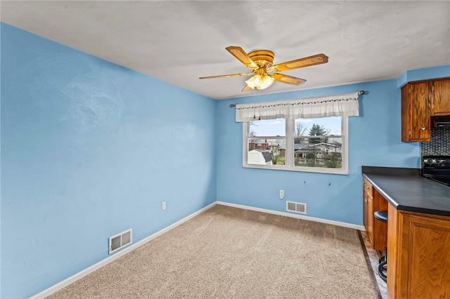 unfurnished dining area featuring ceiling fan and carpet flooring