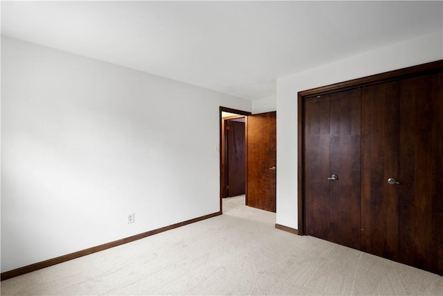 unfurnished bedroom with light colored carpet and a closet