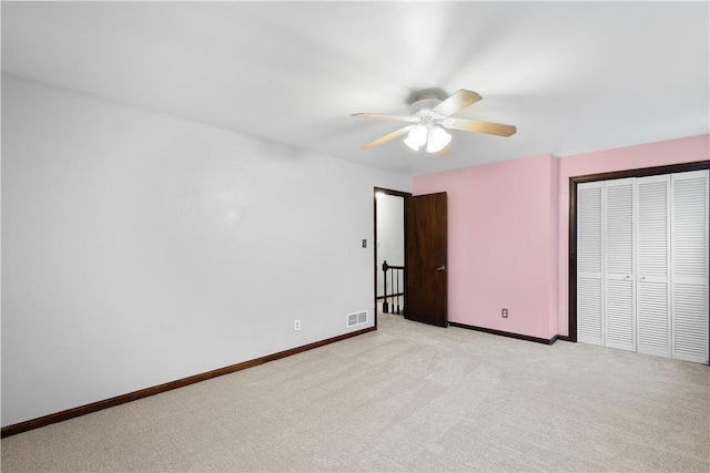 unfurnished bedroom featuring ceiling fan, light colored carpet, and a closet