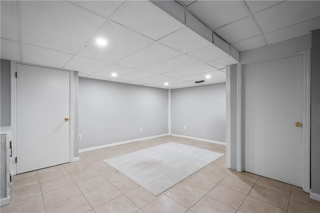 basement with light tile patterned flooring and a drop ceiling