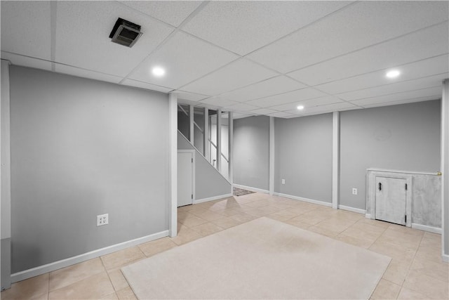 basement featuring a paneled ceiling and light tile patterned flooring