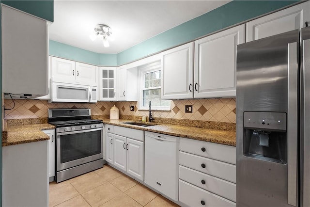 kitchen featuring sink, stone counters, stainless steel appliances, white cabinets, and light tile patterned flooring