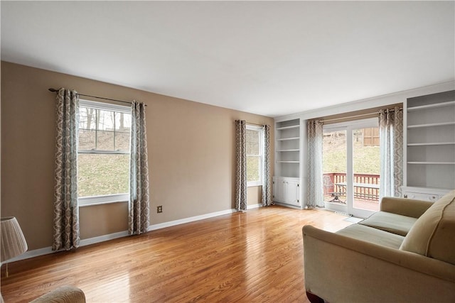 living room featuring built in features and light hardwood / wood-style flooring