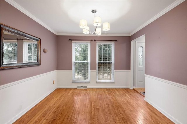 unfurnished dining area featuring a notable chandelier, crown molding, and light wood-type flooring