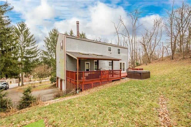 back of property featuring a garage, a hot tub, a deck, and a lawn