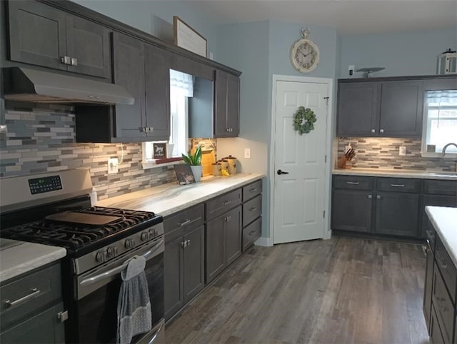 kitchen featuring dark wood-type flooring, sink, tasteful backsplash, and stainless steel gas range oven