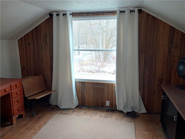 office area with vaulted ceiling, light wood-type flooring, and wooden walls